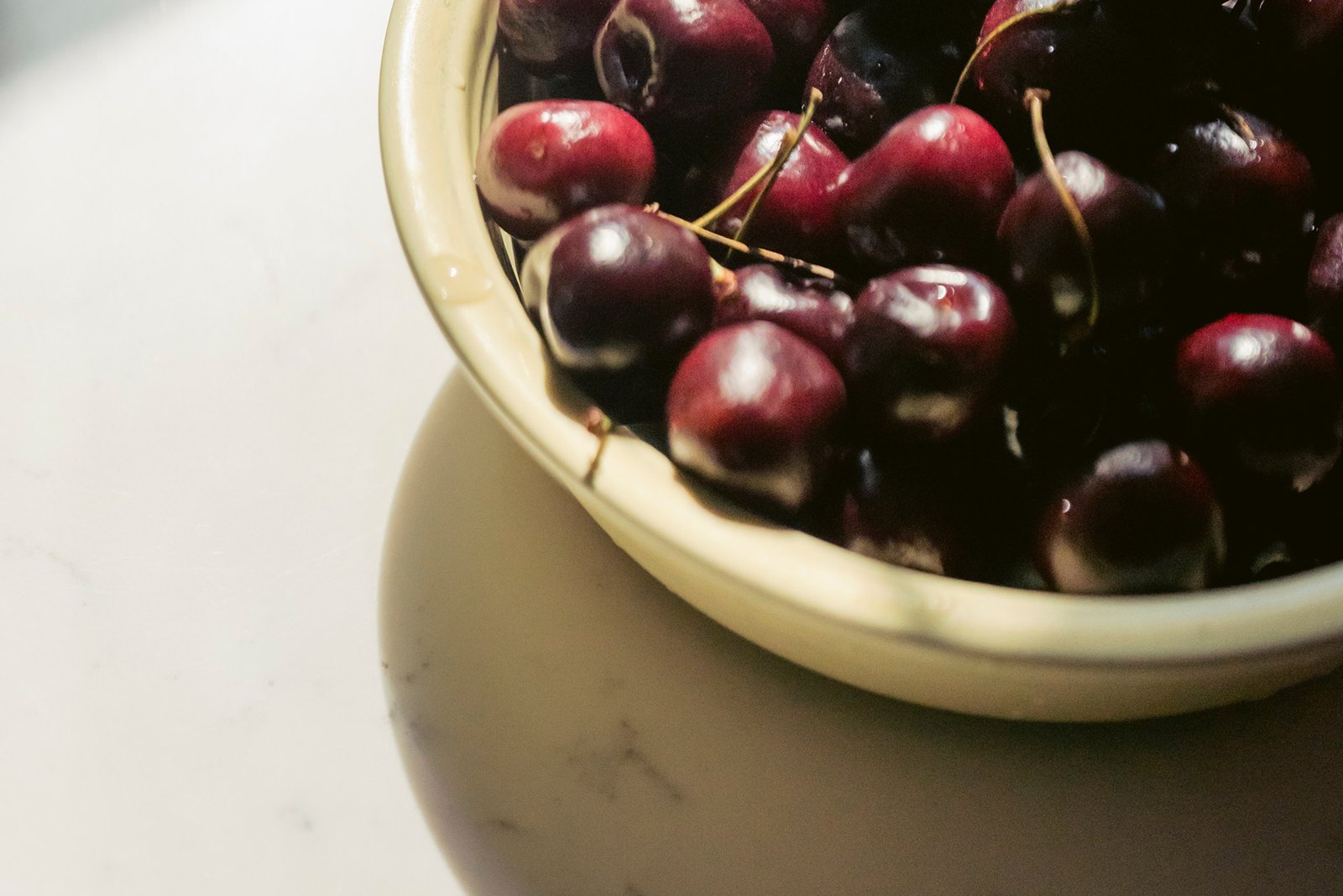 a bowl of cherries on a marble countertop